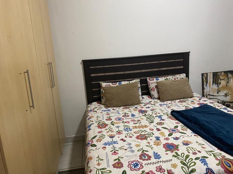 A bedroom featuring a built-in wardrobe with light wood finish and tiled flooring.
