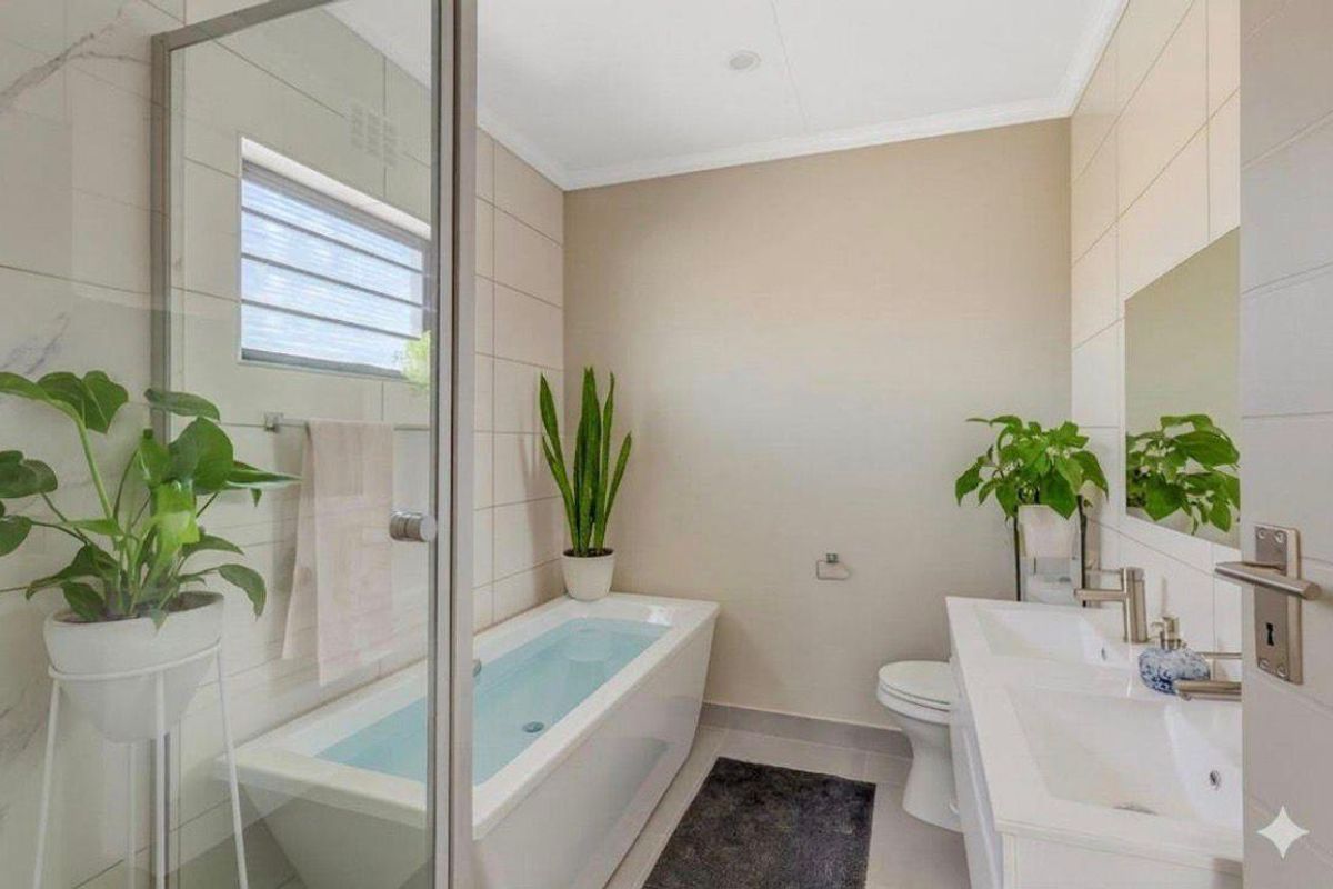 A modern, well-maintained bathroom featuring a built-in bathtub, a glass-enclosed shower, and a double vanity with contemporary fixtures.
