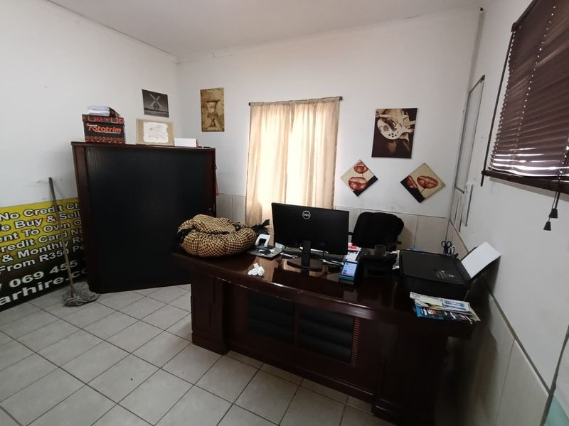 A functional office space featuring tiled flooring and window treatments, suitable for a professional work environment.