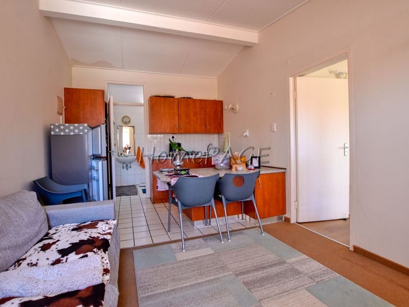 Open plan living and kitchen area featuring built-in cabinetry and tiled kitchen flooring, with direct access to an adjoining bathroom.