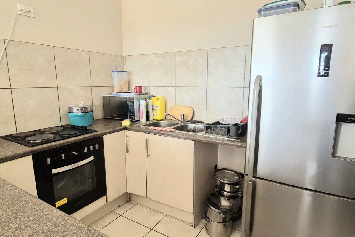 Compact kitchen featuring laminate countertops, tiled backsplash, built-in electric oven, and hob, providing a functional workspace.