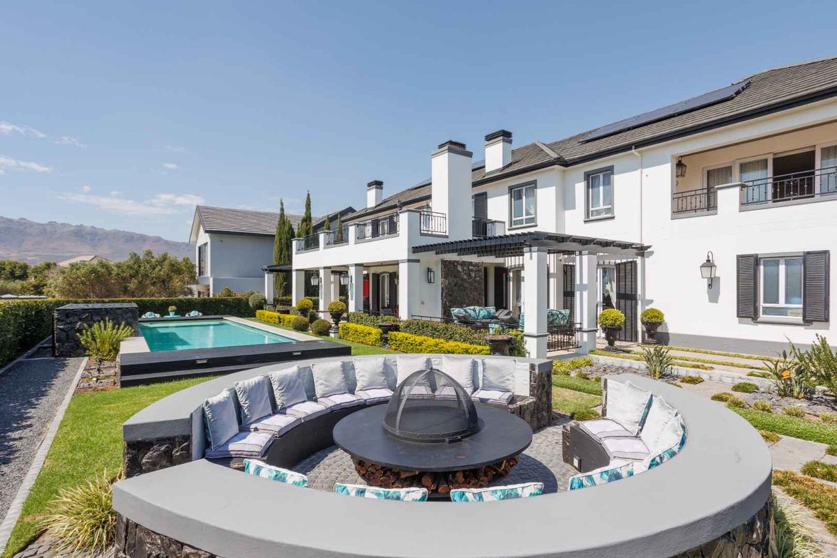 Spacious rear garden featuring a swimming pool, a sunken circular fire pit area, and a covered patio attached to the main residence.