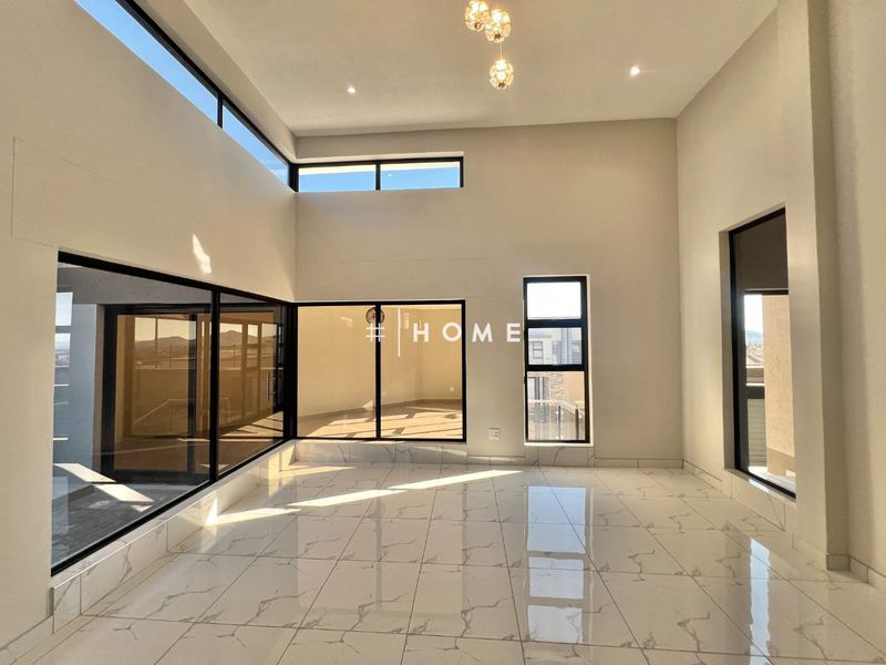 A bright, modern, and spacious living area featuring high ceilings, large windows, and polished porcelain tile flooring, offering an open and airy atmosphere.