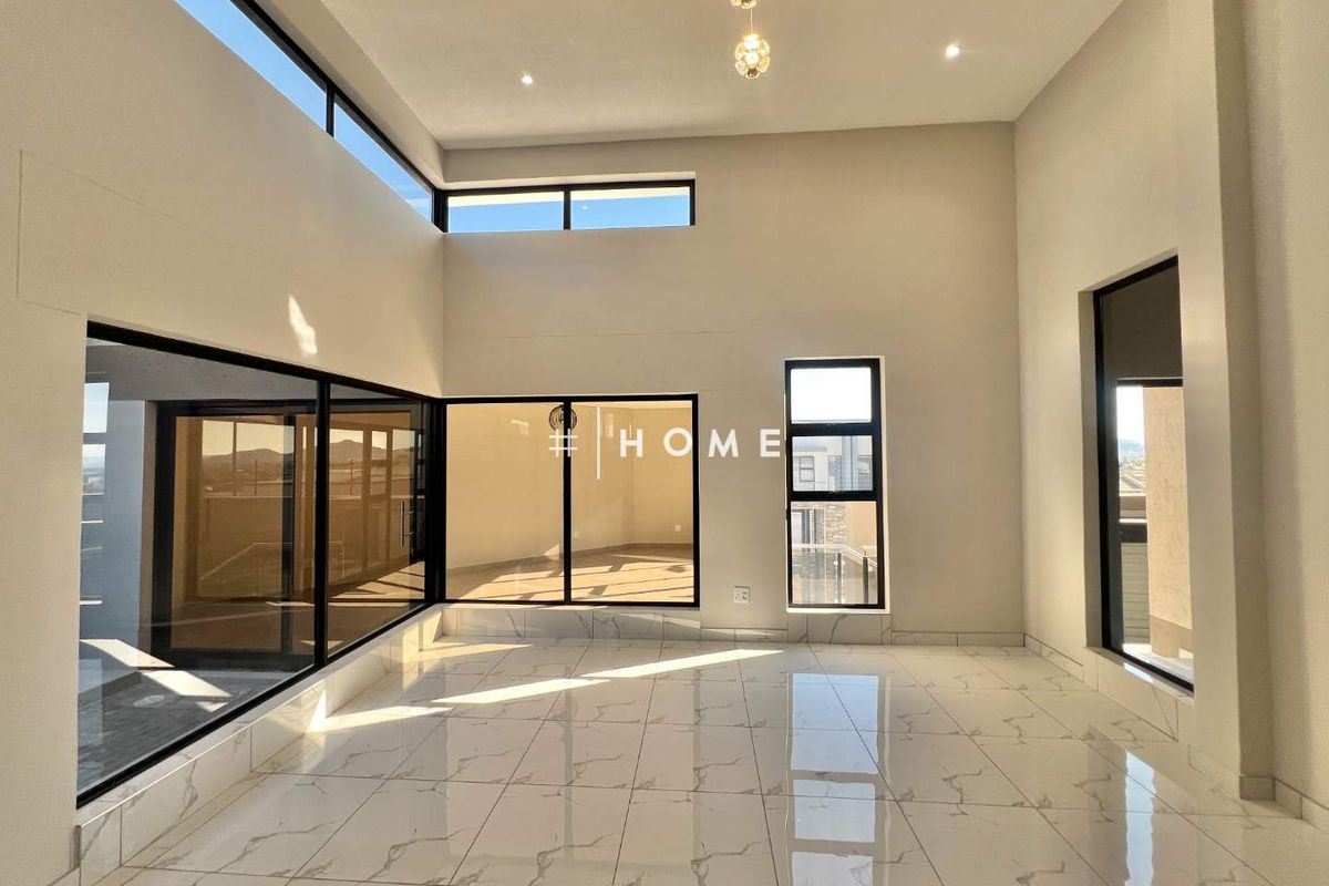 A bright, modern, and spacious living area featuring high ceilings, large windows, and polished porcelain tile flooring, offering an open and airy atmosphere.