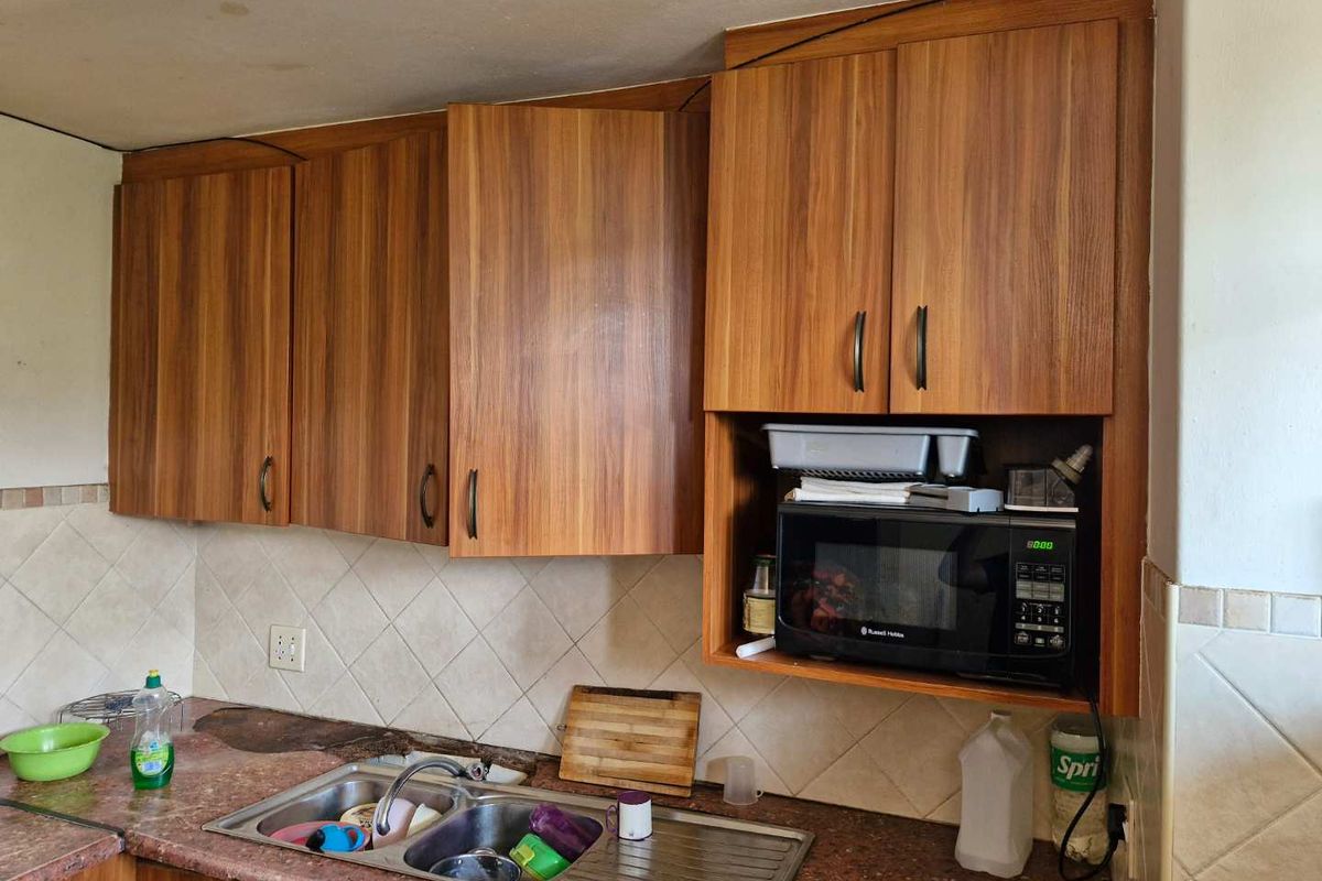 A functional kitchen area featuring wood-grain cabinetry, a double-basin stainless steel sink, and tiled backsplash.