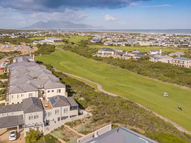 An aerial view of the apartment complex situated adjacent to a golf course, featuring solar panels and well-maintained exterior finishes.