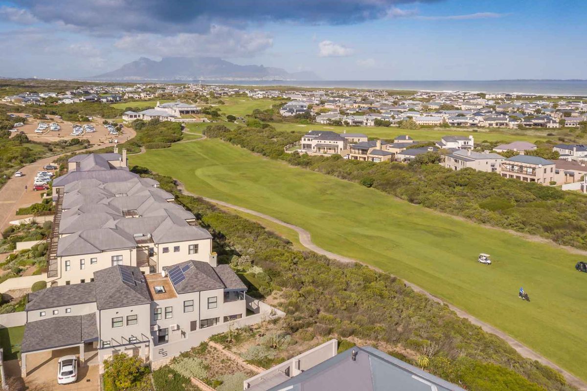 An aerial view of the apartment complex situated adjacent to a golf course, featuring solar panels and well-maintained exterior finishes.