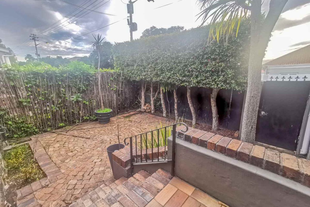 A private rear courtyard featuring brick paving, a retaining wall, and established hedge screening, providing a functional outdoor space.