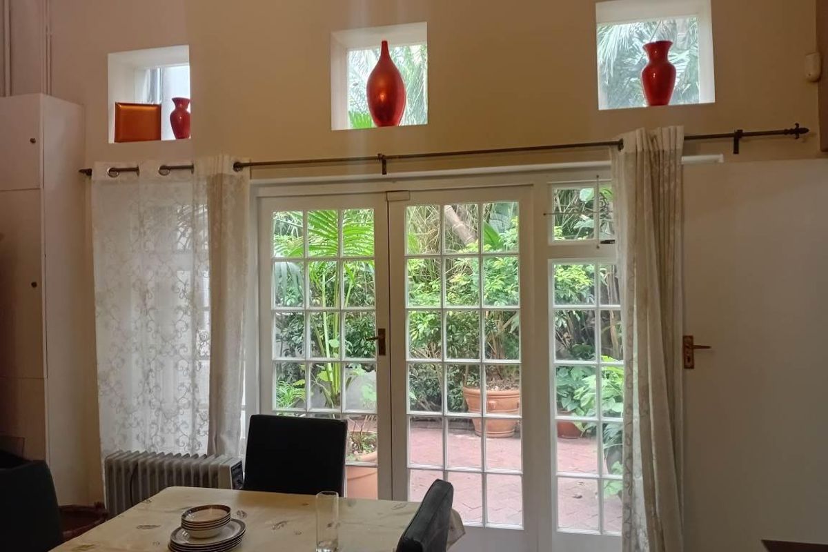 Living area featuring classic French doors opening to a garden patio, complemented by high-level clerestory windows that provide natural light.