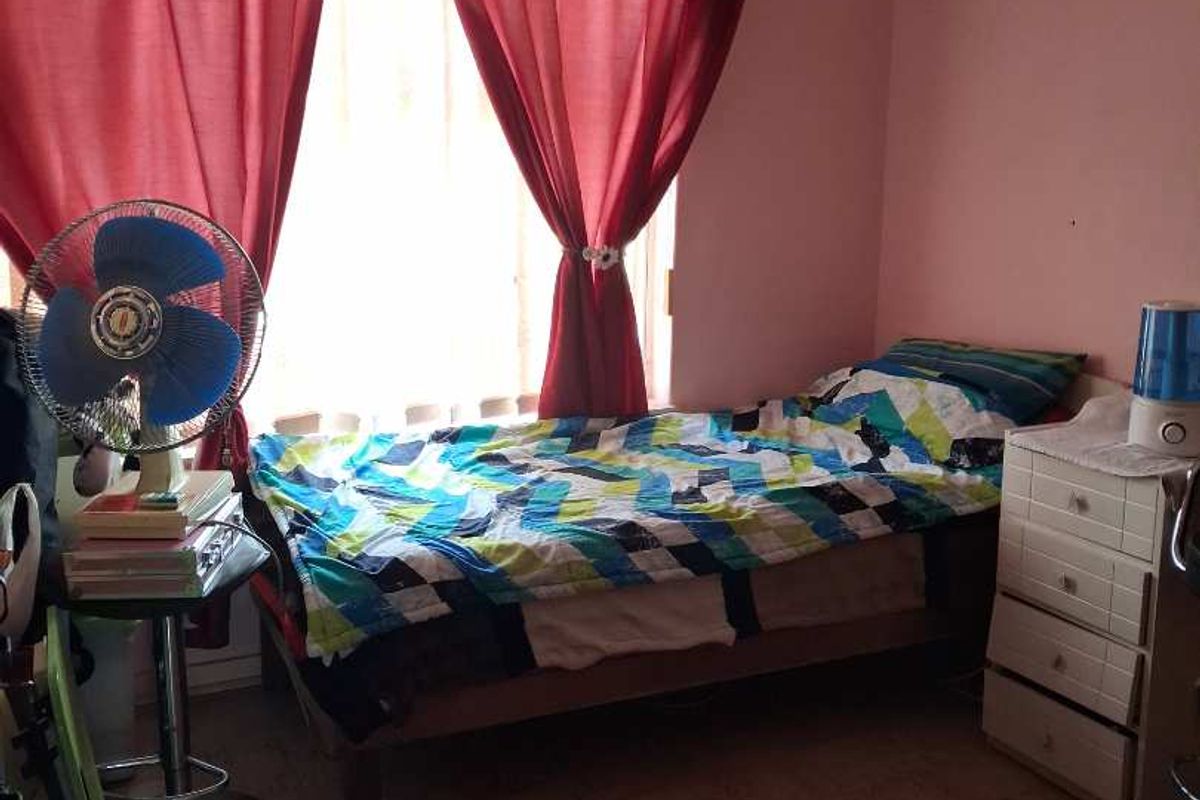 A bedroom featuring parquet flooring, a window with curtain fixtures, and a ceiling ventilation vent.
