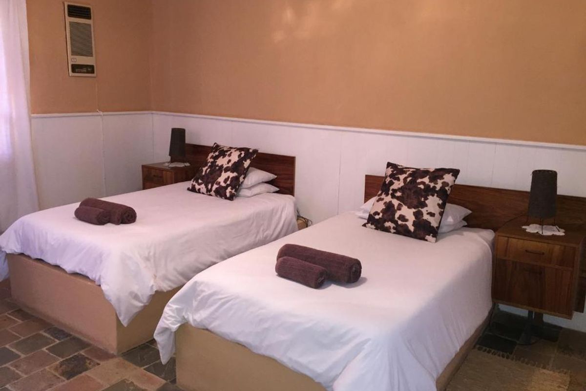 A bedroom featuring stone tile flooring, wainscoting, and a wall-mounted air conditioning unit.