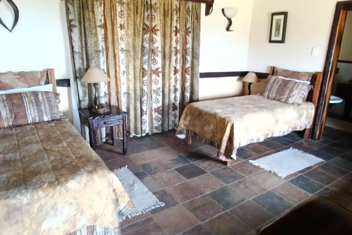 A rustic bedroom featuring slate tile flooring, wooden trim details, and an en-suite bathroom access.