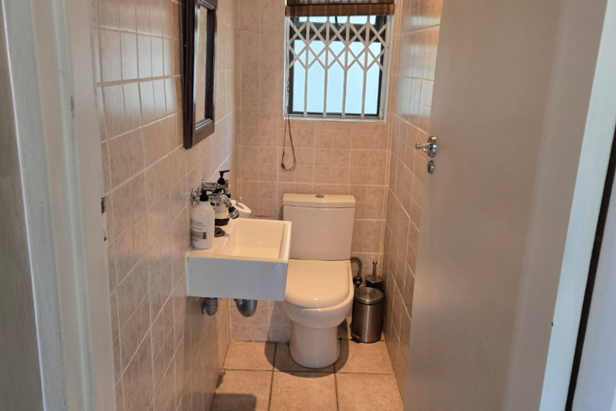 Compact guest bathroom featuring a wall-mounted basin, toilet, and neutral ceramic tiling throughout.