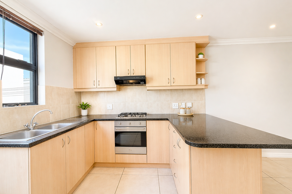 A clean and functional kitchen featuring light wood cabinetry, granite countertops, a gas hob, built-in oven, and tiled flooring with ample workspace.