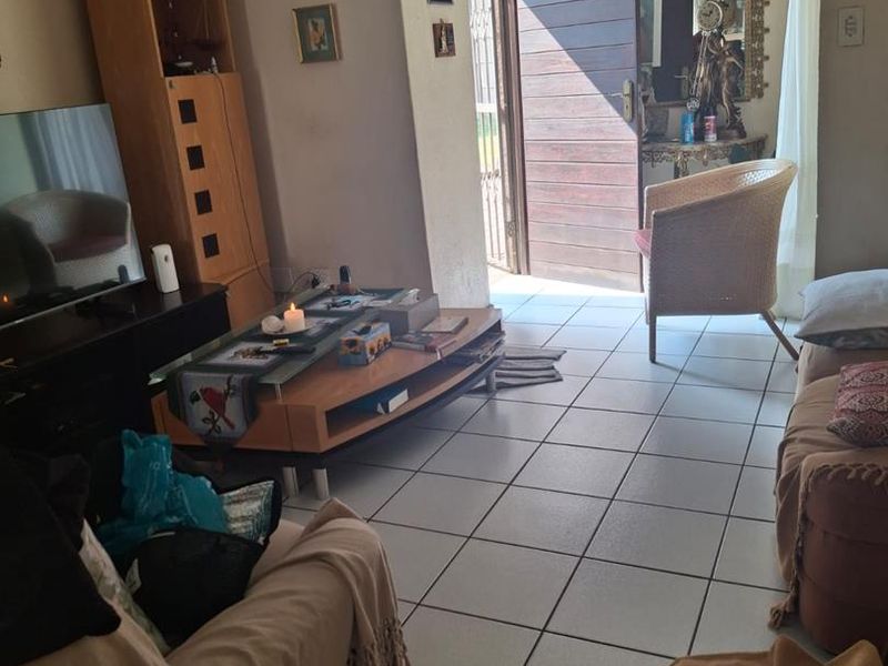 A living room area featuring tiled flooring and direct access to the exterior through a timber entrance door.