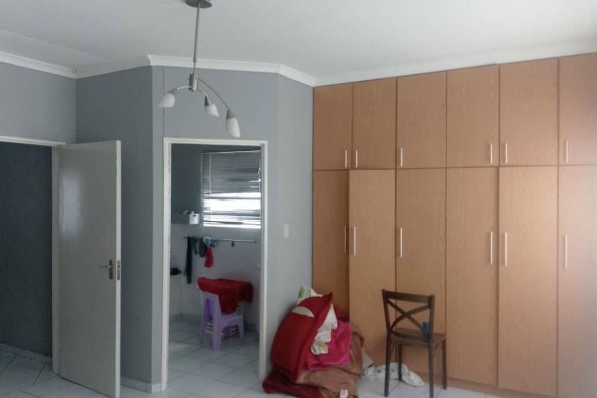 A bedroom featuring extensive built-in wooden cabinetry, tiled flooring, and an adjoining en-suite bathroom area.