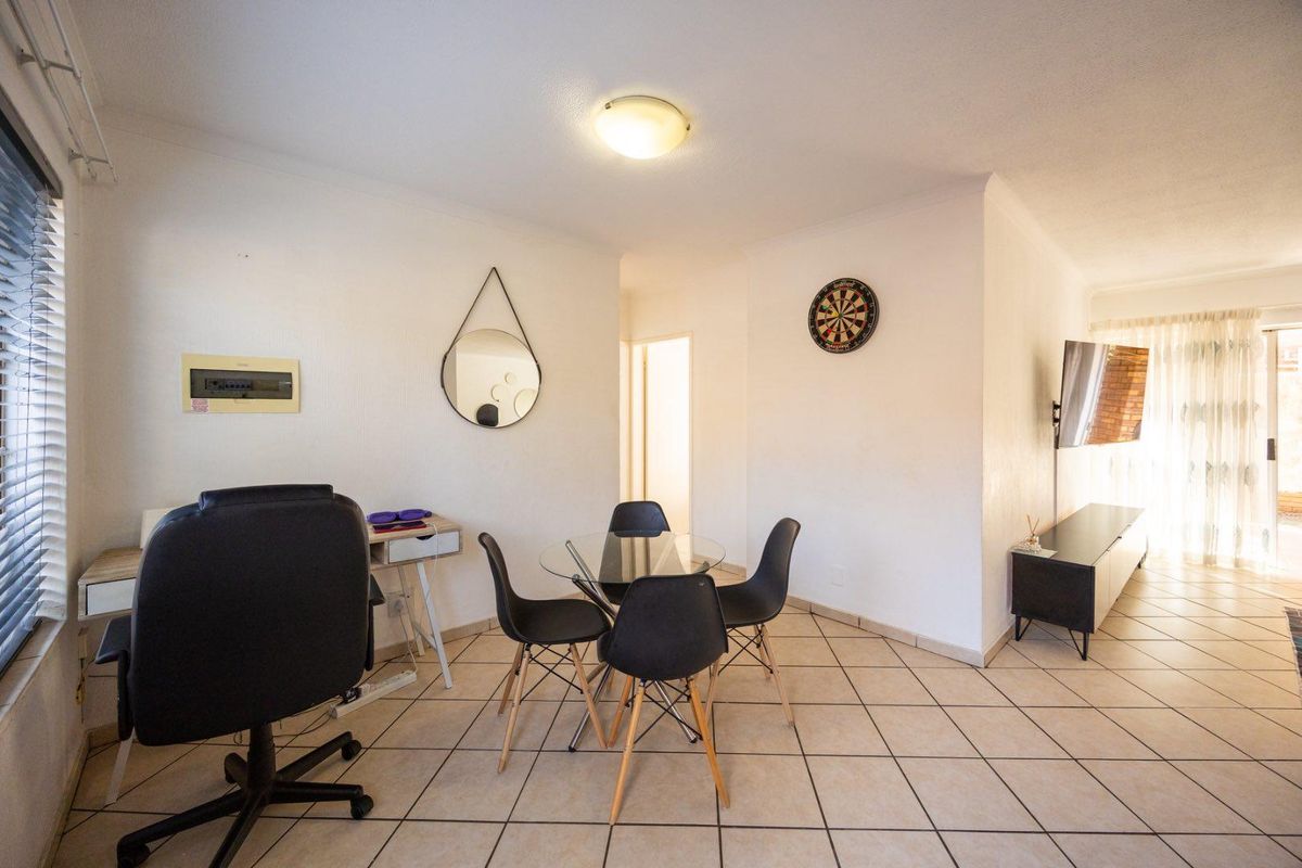 Open-plan living area featuring tiled flooring, neutral walls, and a sliding glass door providing access to the exterior.
