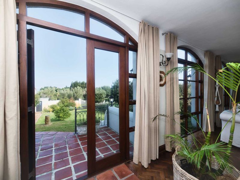 Bright living area featuring elegant arched timber-framed glass doors that open onto a terracotta-tiled patio and garden.