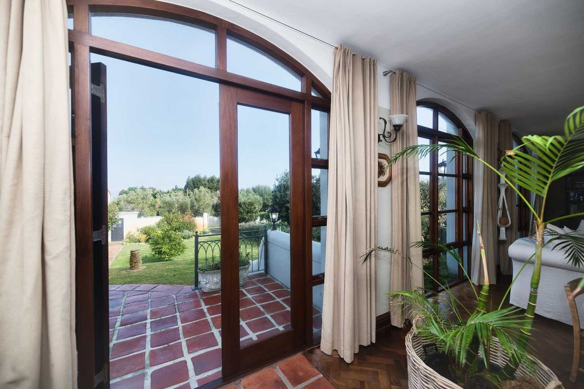 Bright living area featuring elegant arched timber-framed glass doors that open onto a terracotta-tiled patio and garden.
