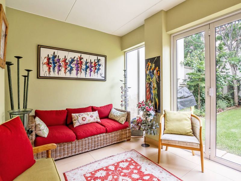 A bright living room featuring tiled flooring and large aluminium sliding doors that provide direct access to the garden.