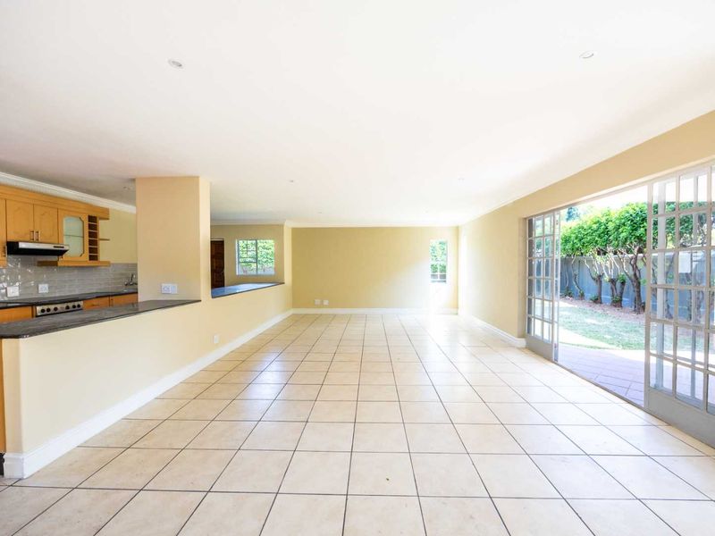 Spacious open-plan living and kitchen area featuring tiled floors, built-in cabinetry, and large sliding doors providing direct access to the garden.