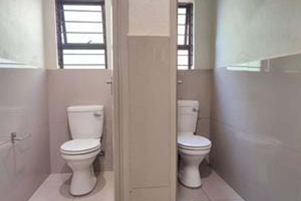 A functional bathroom space featuring dual toilets, tiled walls, and tiled flooring, providing a clean and practical layout.
