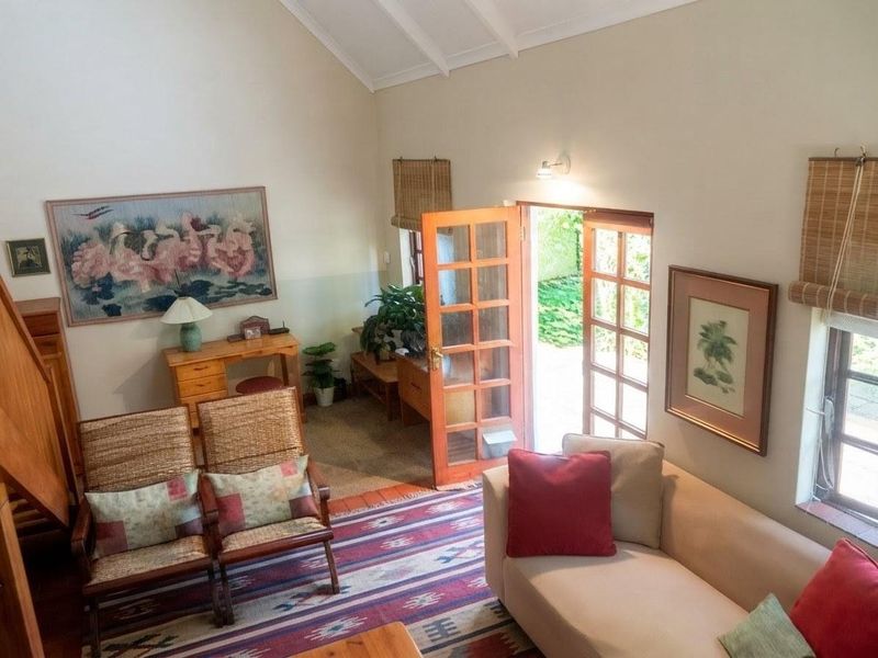 A cozy living room featuring a high vaulted ceiling with exposed rafters and direct access to the garden through classic timber french doors.