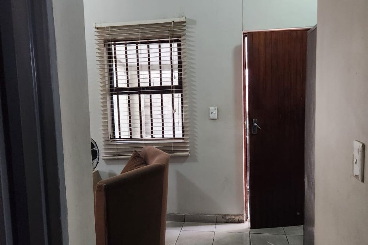A bedroom featuring tiled flooring, a window with security bars and venetian blinds, and a solid timber door.