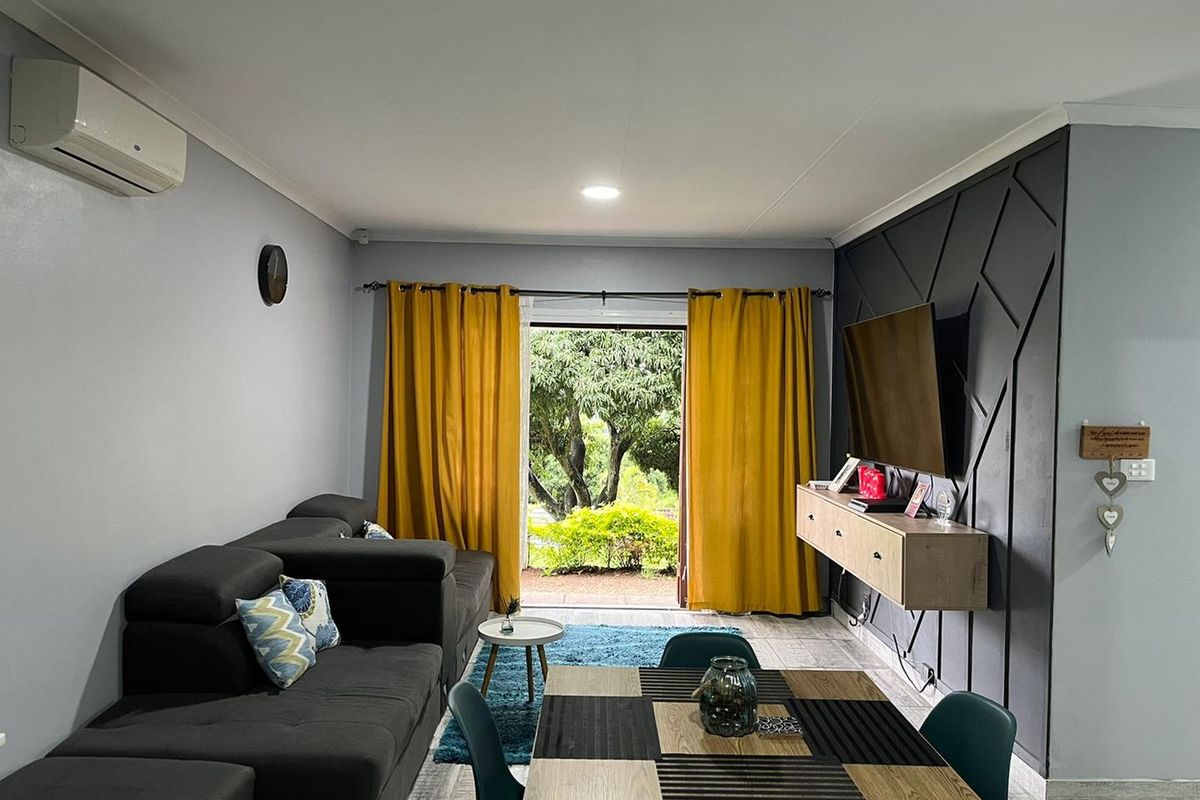 Open-plan living area featuring a modern feature wall, tiled flooring, split-system air conditioning, and direct access to the outdoor garden space.