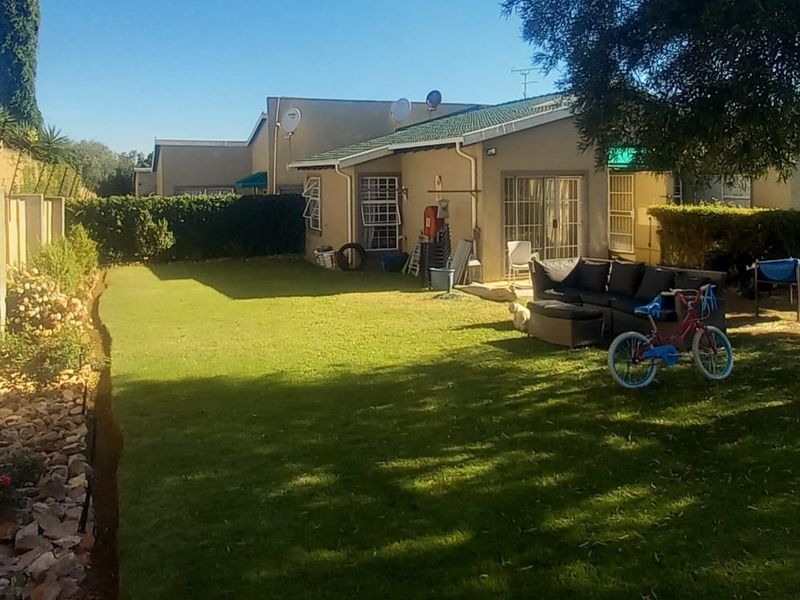 A private rear garden featuring a well-maintained lawn, boundary wall, and direct access to the townhouse via sliding glass doors.