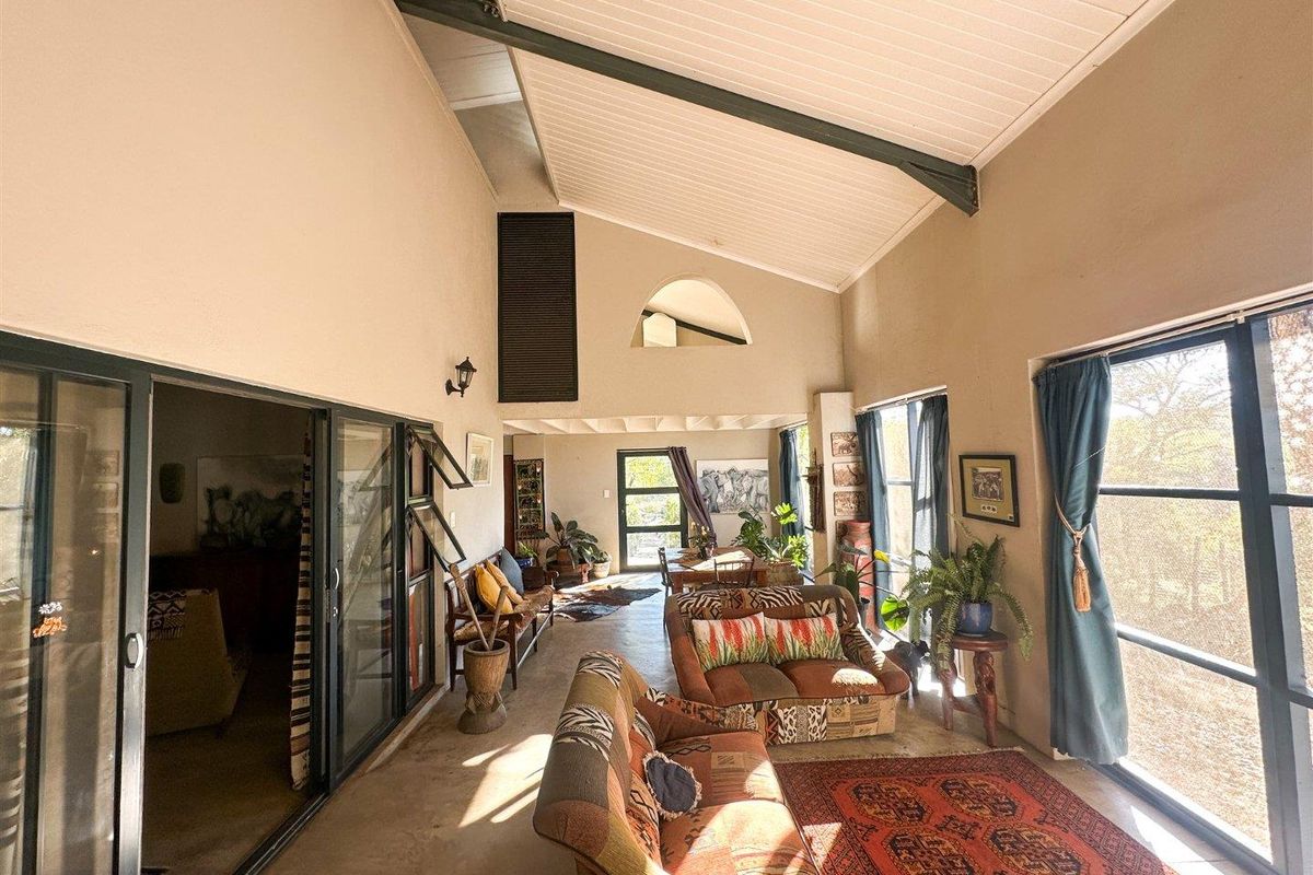 Spacious living area featuring high vaulted ceilings, exposed structural beams, large sliding glass doors, and polished concrete flooring with abundant natural light.