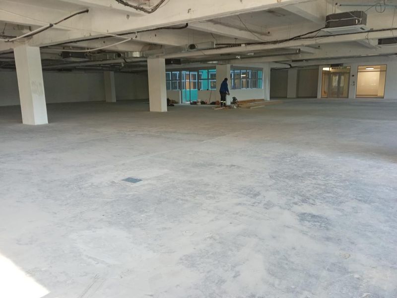 A large, open-plan commercial space featuring exposed concrete ceilings, structural columns, and unfinished flooring, suitable for custom office or retail fit-out.