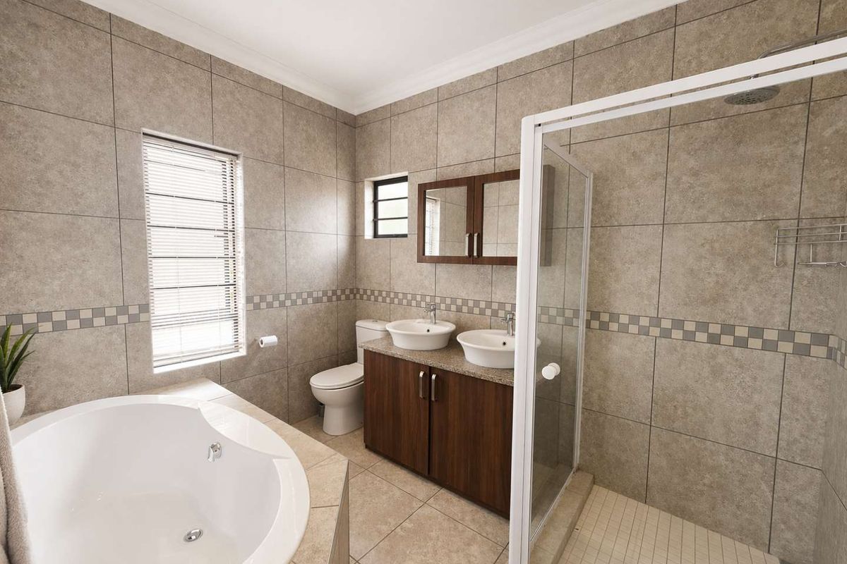 A well-appointed bathroom featuring a corner bathtub, a glass-enclosed shower, and a double vanity with integrated sinks and storage cabinetry.
