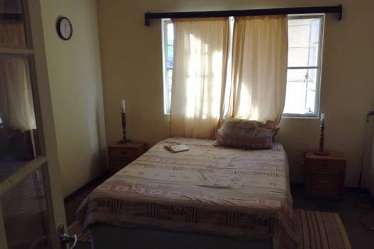 A functional bedroom featuring a window with curtain rod and neutral wall finishes.