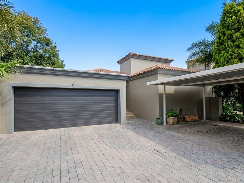 Front exterior view featuring a double garage, a covered carport, and a paved driveway with well-maintained stucco walls and tiled roofing.