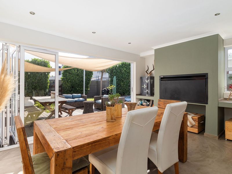 Open-plan living area featuring a built-in fireplace, polished concrete floors, and seamless indoor-outdoor flow through large bi-fold doors to the patio.