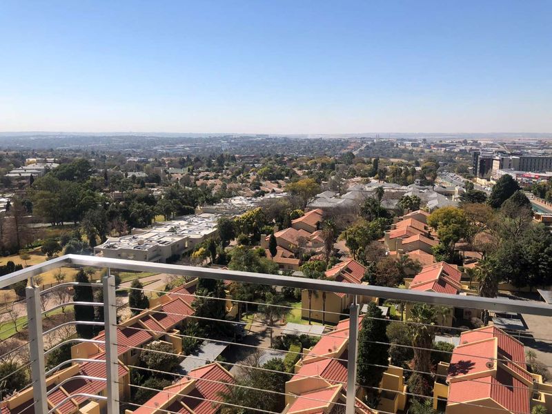 Elevated panoramic view of the surrounding residential neighborhood and landscape, captured from a balcony with a modern stainless steel cable balustrade.