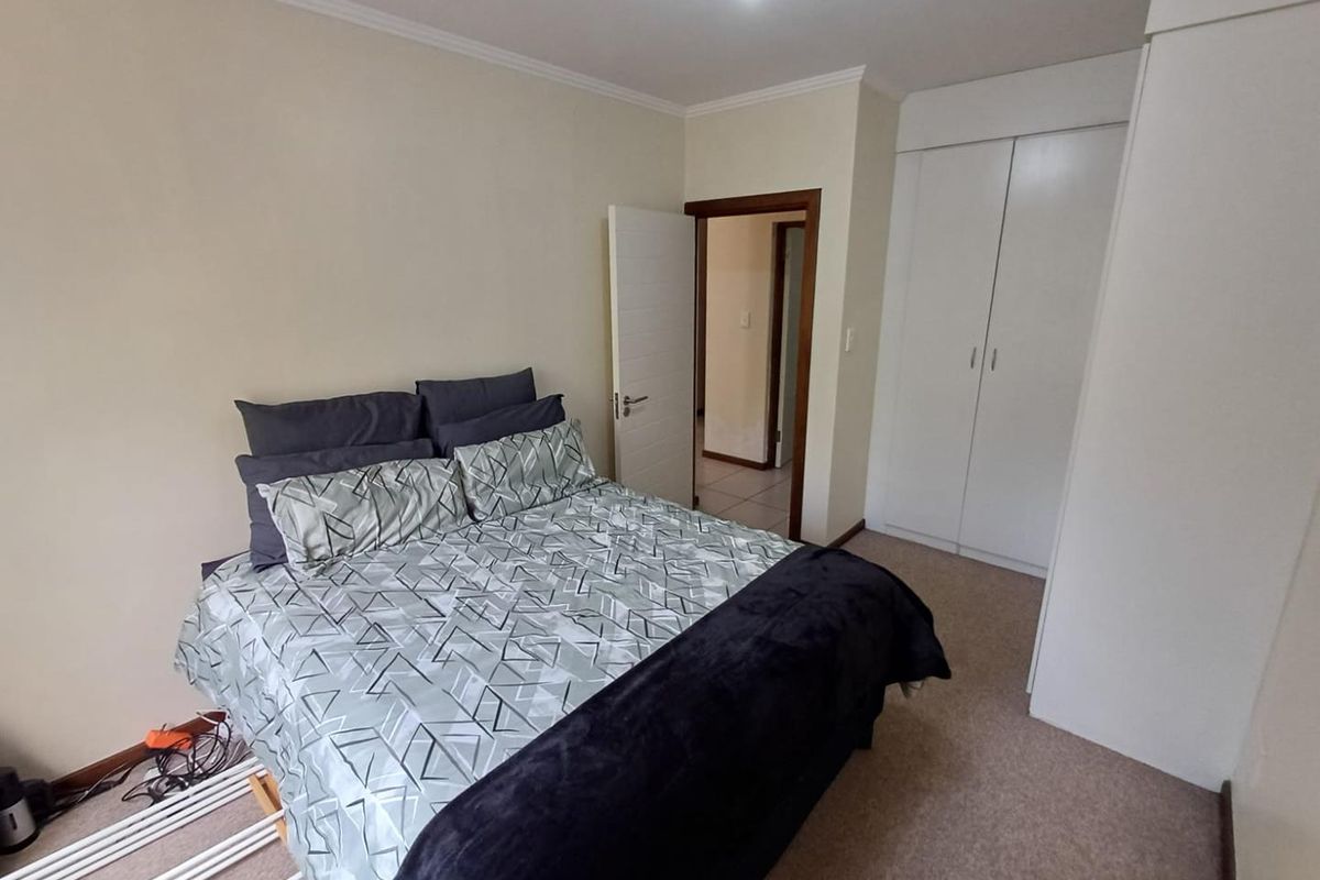 A functional bedroom featuring neutral wall finishes, carpeted flooring, and built-in cupboards providing ample storage space.