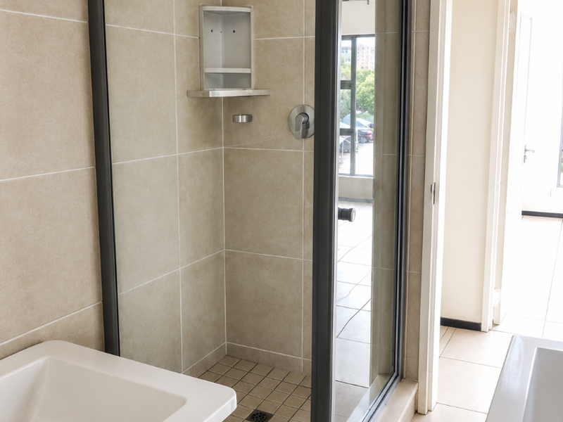 A clean, modern bathroom featuring a glass-enclosed shower with built-in niche, tiled walls, and a bathtub.