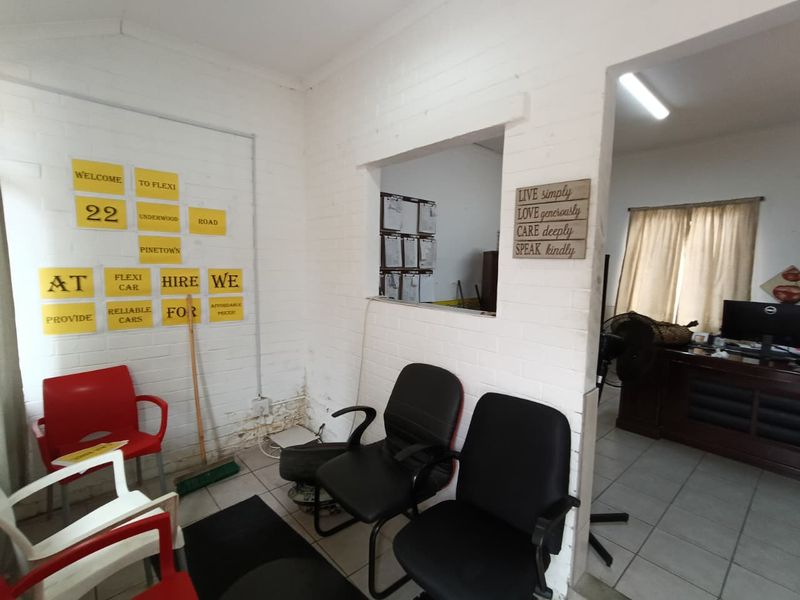 Office reception area featuring a serving hatch, tiled flooring, and painted brick walls with visible signs of damp and wear.