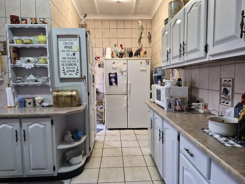 A functional kitchen featuring white cabinetry, laminate countertops, and tiled wall finishes with a classic layout.