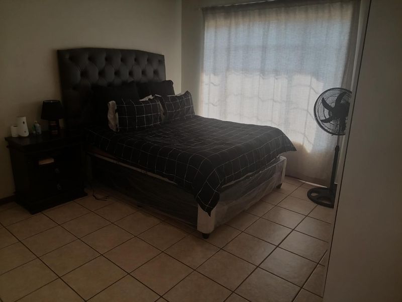 A bedroom featuring tiled flooring and a built-in cupboard, currently furnished with a bed and bedside table.