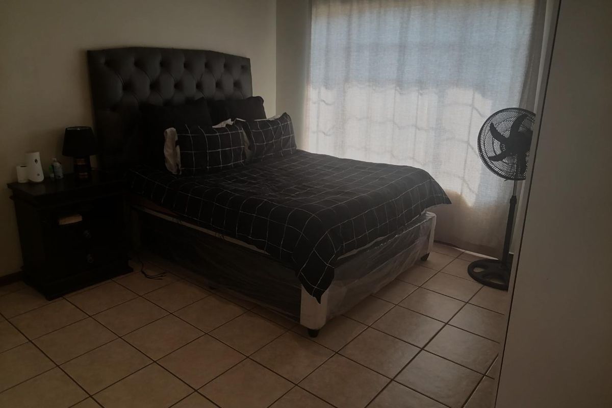 A bedroom featuring tiled flooring and a built-in cupboard, currently furnished with a bed and bedside table.