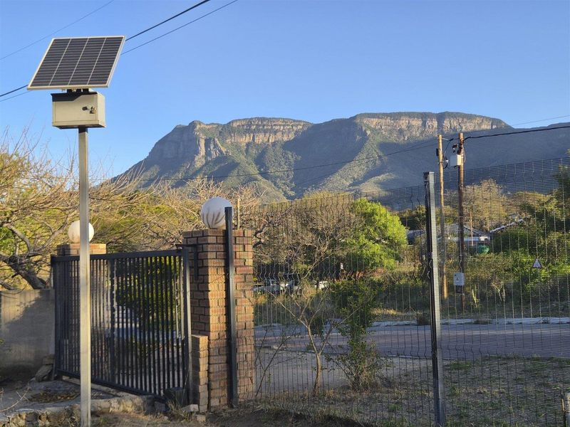 A scenic view of the surrounding mountains featuring a solar-powered security light and perimeter fencing.