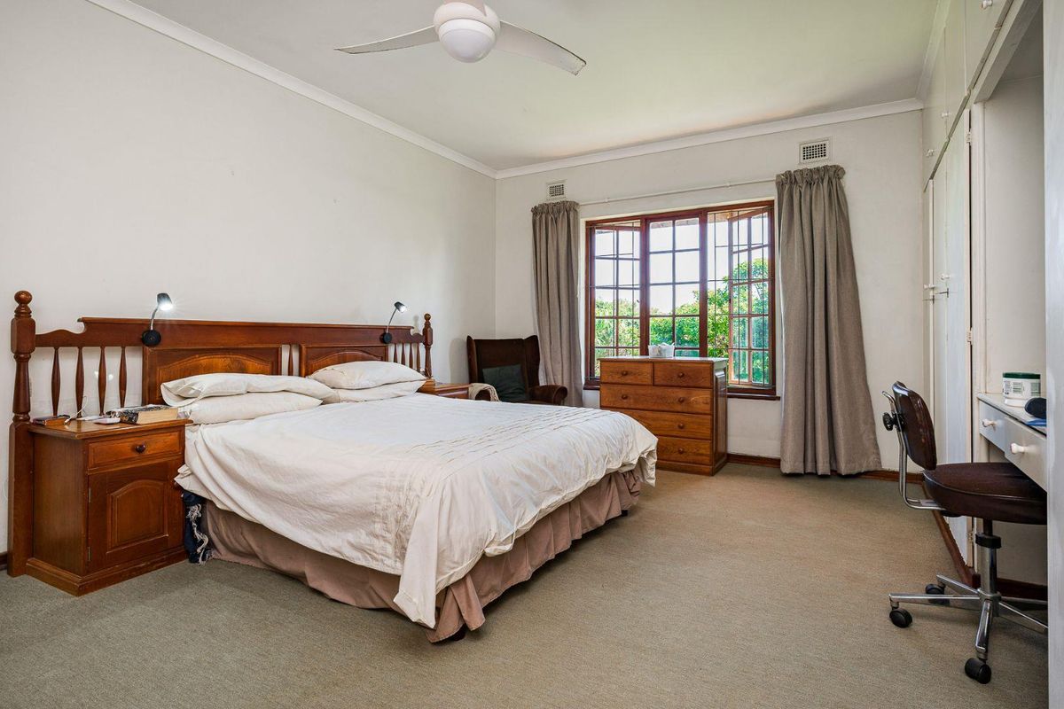 Spacious bedroom featuring built-in cabinetry, a ceiling fan, and large windows that provide natural light and garden views.