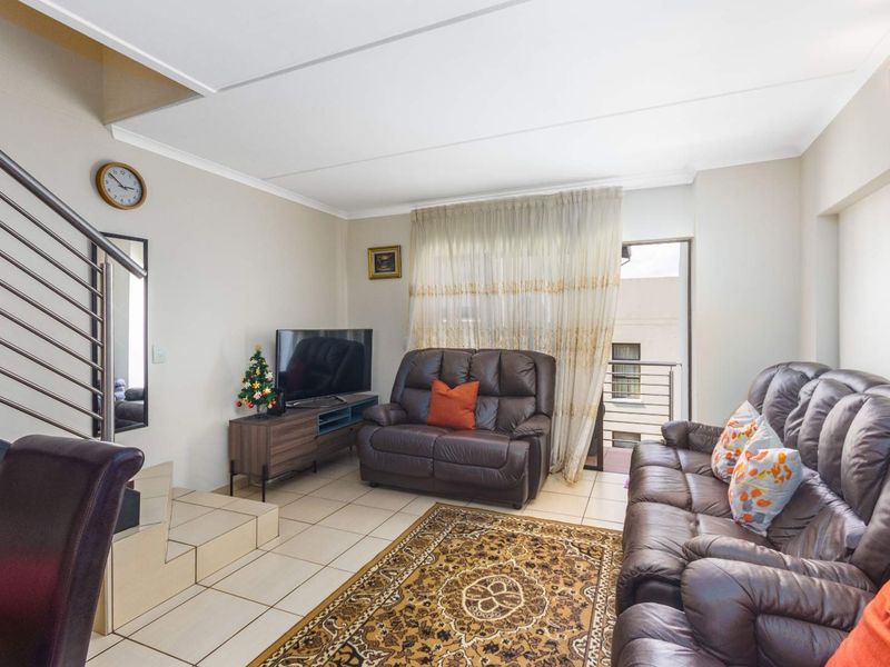 A living room featuring tiled flooring, a staircase with a metal railing, and a sliding glass door providing access to a balcony.