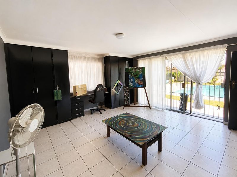 Spacious living area featuring tiled flooring, built-in storage cupboards, and large sliding glass doors providing direct access to the outdoor pool area.