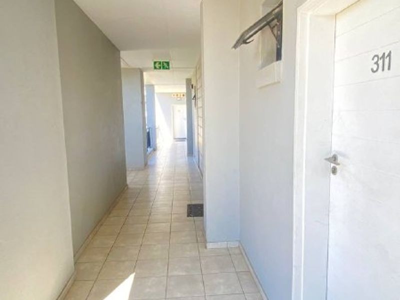 A clean, well-lit apartment hallway featuring tiled flooring and a secure entrance door for unit 311.
