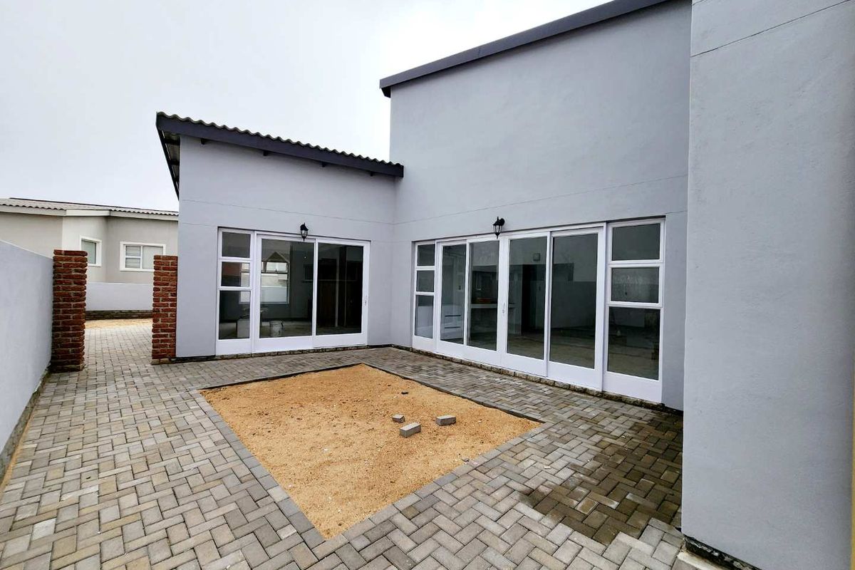 A rear courtyard featuring paved flooring and large sliding glass doors providing seamless access to the interior living spaces.