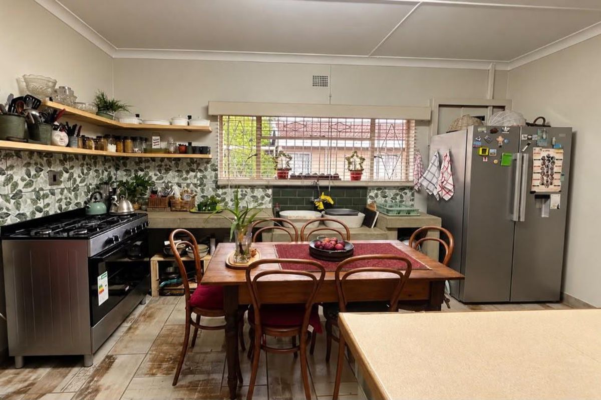 A functional kitchen featuring a gas stove, concrete countertops, double basin sink, and decorative tiled backsplash with open timber shelving.
